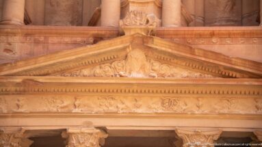 Close view of the triangular pediment, entablature, and weathered sandstone carving on Al-Khazneh’s lower façade.