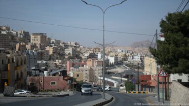 Descending street through a dense hillside town of pale buildings and streetlights near Petra.