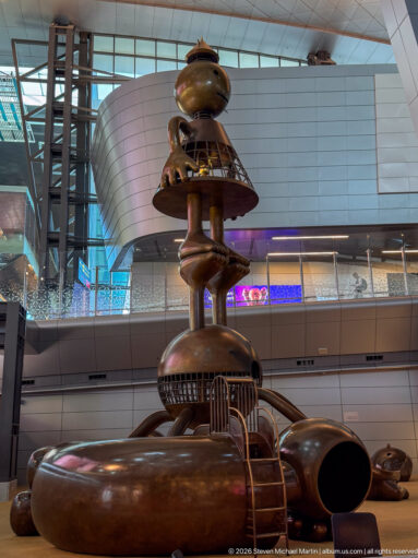 Low-angle detail of Tom Otterness’s Other Worlds with monumental bronze forms inside Hamad International Airport.