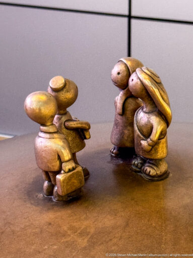 Three miniature bronze figures facing one another in Tom Otterness’s Other Worlds at Hamad International Airport.