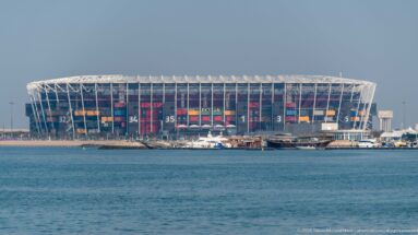 Stadium 974 viewed across the Doha waterfront, with its exposed frame and colorful shipping-container modules.