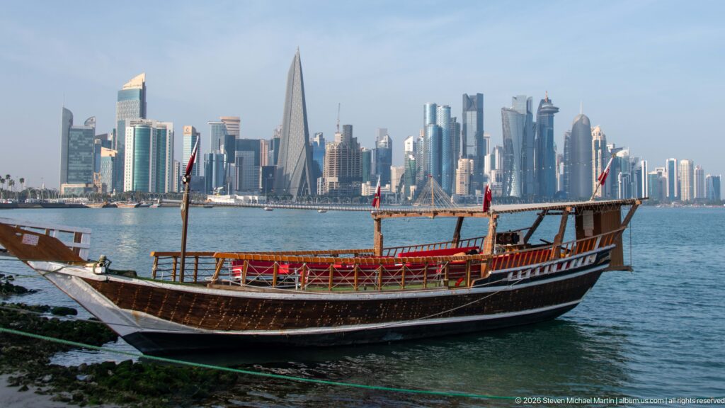 Traditional wooden dhow moored beside Doha Bay with the modern West Bay skyline across the water.