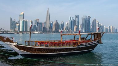 Traditional wooden dhow moored beside Doha Bay with the modern West Bay skyline across the water.