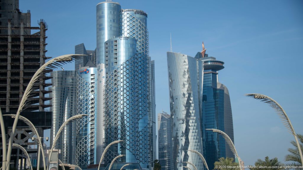 Cluster of West Bay high-rises with patterned glass façades and curved palm-like streetlights in the foreground.