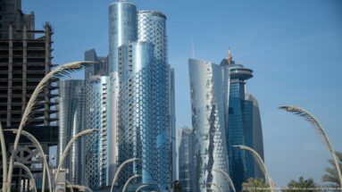 Cluster of West Bay high-rises with patterned glass façades and curved palm-like streetlights in the foreground.