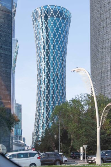 Doha Tower, a rounded high-rise wrapped in a dense diamond-patterned external screen.
