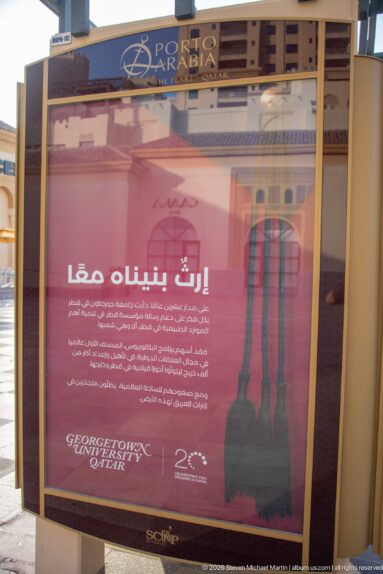 Red Arabic-language Georgetown University in Qatar advertisement with a 20-year anniversary emblem.
