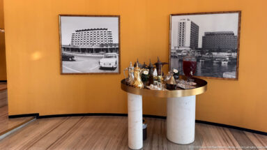 Traditional dallah coffee pots and refreshments on a round table beneath two historic black-and-white hotel photographs.