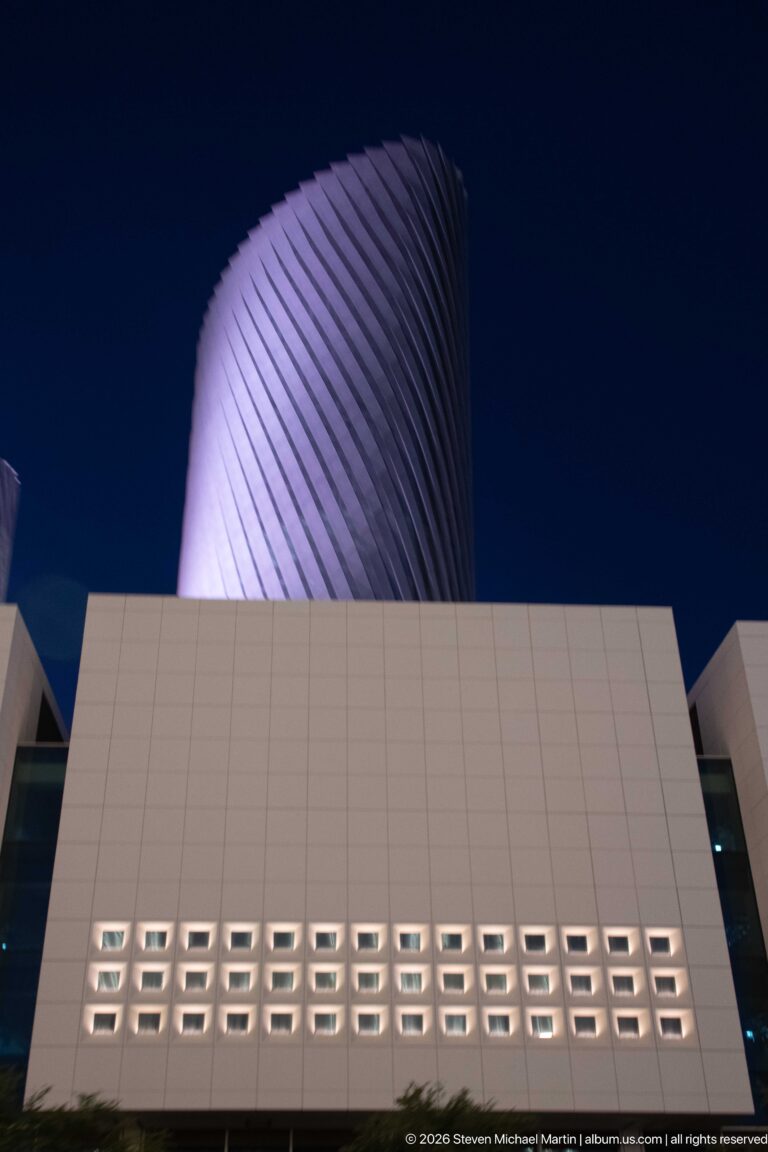 Twisting Lusail tower rises behind a white podium with rows of recessed square openings.