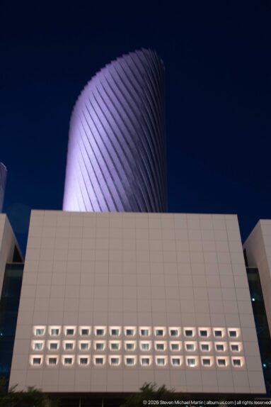 Twisting Lusail tower rises behind a white podium with rows of recessed square openings.