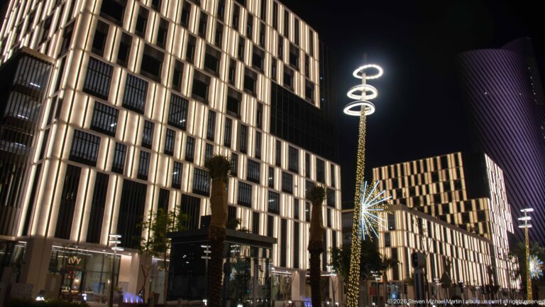 Illuminated modern blocks and a decorative ringed streetlight line Lusail Boulevard at night.