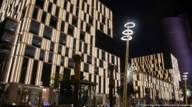 Illuminated modern blocks and a decorative ringed streetlight line Lusail Boulevard at night.