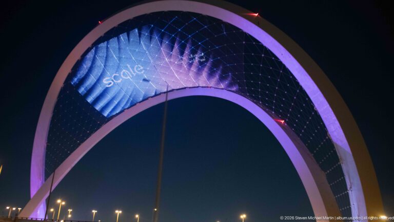 Close upward view of the pink 5/6 Arch with purple-blue graphics across its suspended digital mesh.
