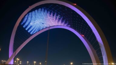 Close upward view of the pink 5/6 Arch with purple-blue graphics across its suspended digital mesh.