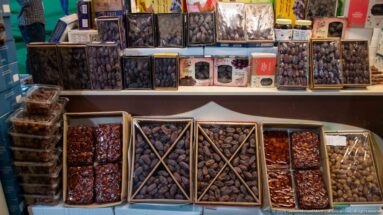 Open boxes and containers filled with assorted dark and reddish-brown dates displayed on a Souq Waqif food counter.