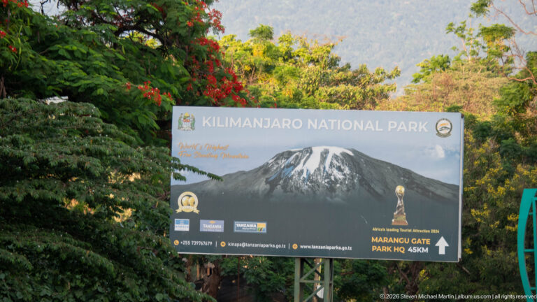 Kilimanjaro National Park roadside sign with mountain graphic and arrow directing toward Marangu Gate, 45 kilometers away.