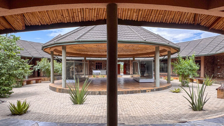 Symmetrical museum courtyard with a circular columned pavilion, paved paths, and aloe-like plants.