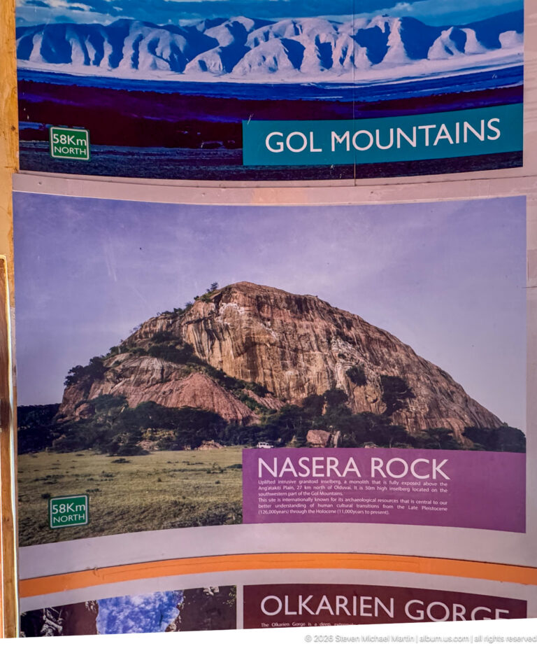 Interpretive panel labeled “Gol Mountains” and “Nasera Rock,” with a large isolated rocky hill above grassland.