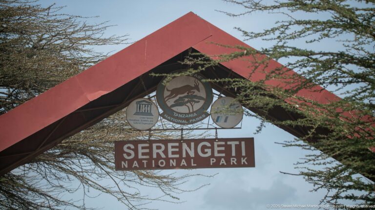 Red gabled Serengeti National Park entrance structure with official emblems and large white park-name lettering.