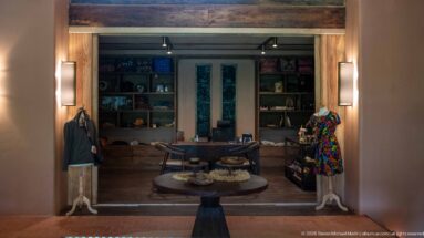 Small lodge boutique with two mannequins, central round display table and shelves of crafts and merchandise at the back.
