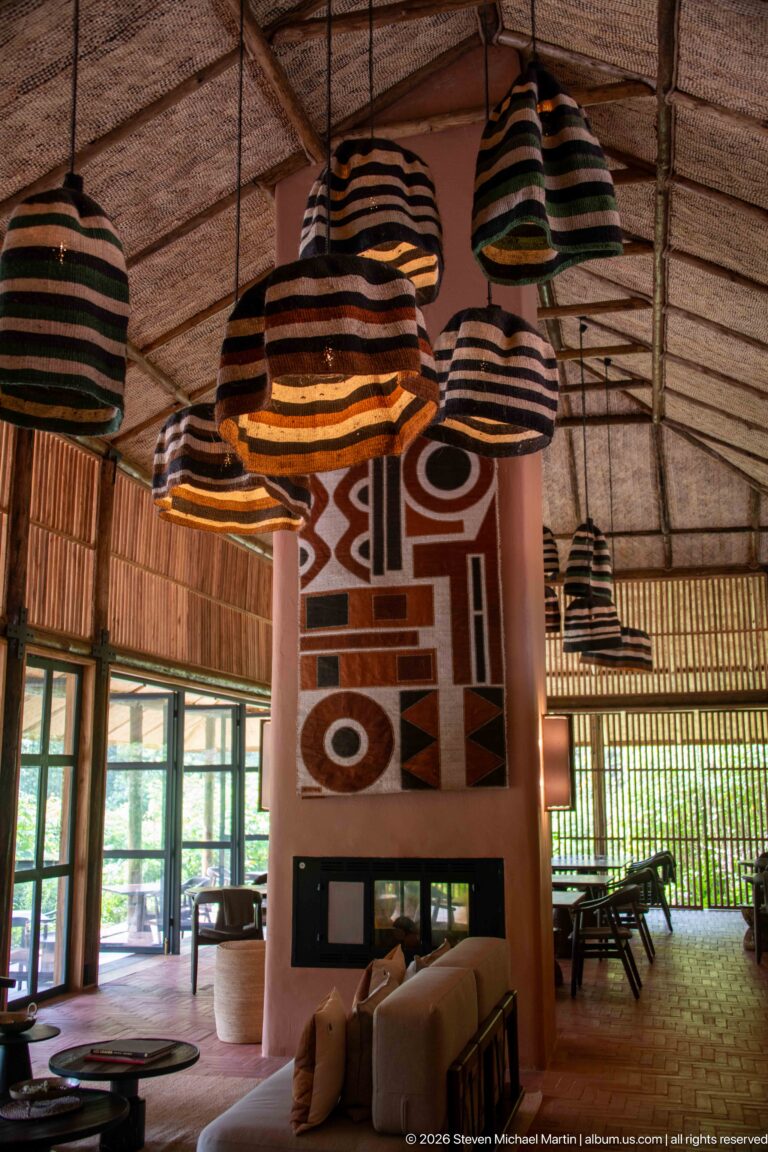 Striped pendant shades hanging above lounge seating and a fireplace wall decorated with a bold geometric textile.