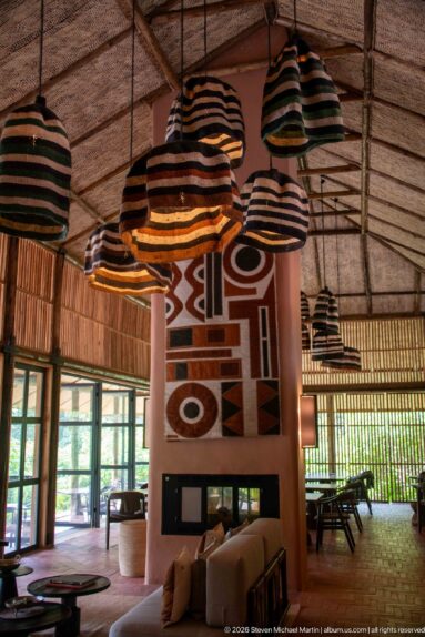 Striped pendant shades hanging above lounge seating and a fireplace wall decorated with a bold geometric textile.