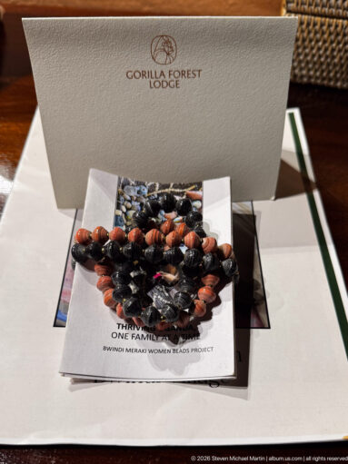 Beaded jewelry resting on printed Bwindi women’s project material beneath a Gorilla Forest Lodge card.