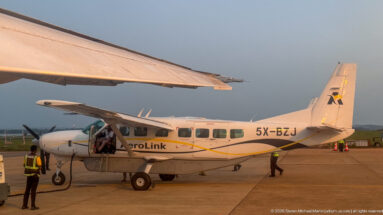 Aerolink Uganda Cessna Grand Caravan 5X-BZJ on the apron with ground staff and passengers.