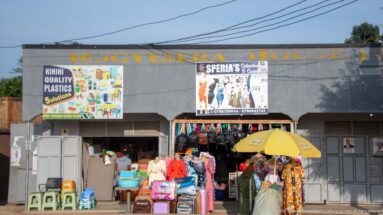 Kihihi Quality Plastics Solutions displays plastic chairs, basins, containers, luggage and clothing beneath storefront signs.