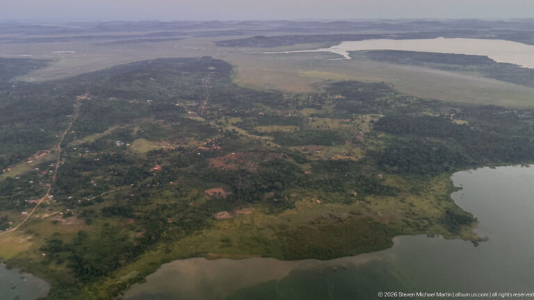 Wooded peninsula with scattered settlement, roads, wetlands, and broad water on several sides.