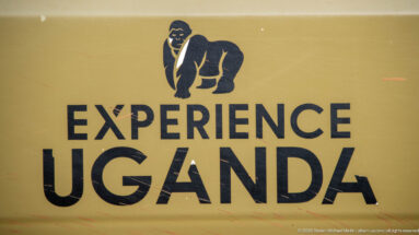 Yellow sign with a stylized gorilla above the large black words EXPERIENCE UGANDA.