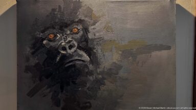 Expressionistic gorilla portrait in black and gray paint with prominent orange-brown eyes.