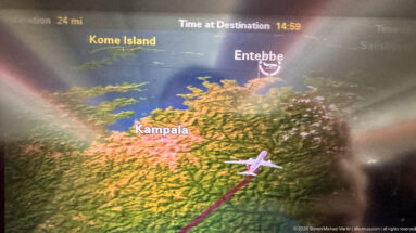 In-flight map screen showing an aircraft approaching Uganda with Entebbe and Kampala labeled and a magenta route line.
