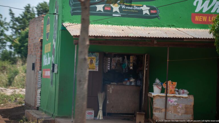 Green Nile Special-branded roadside storefront with an open doorway, corrugated roof, and small display of goods.