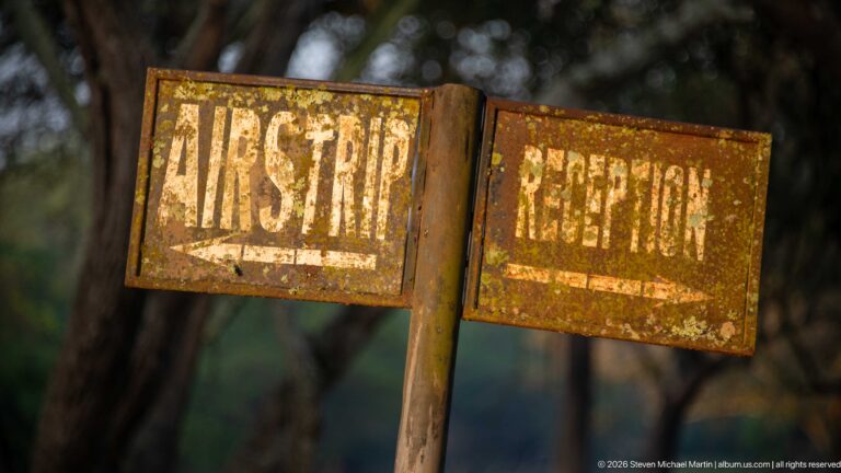 Two weathered metal signs labeled FIRST AID and RECEPTION with arrows pointing in opposite directions.