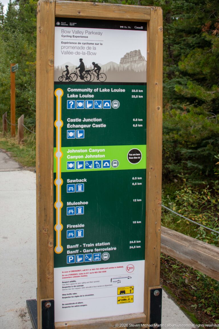 Roadside route sign lists Johnston Canyon and other Bow Valley Parkway stops with distances and facility symbols.