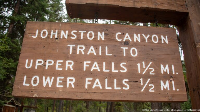 Wooden Johnston Canyon sign lists the trail distances to Upper Falls and Lower Falls.