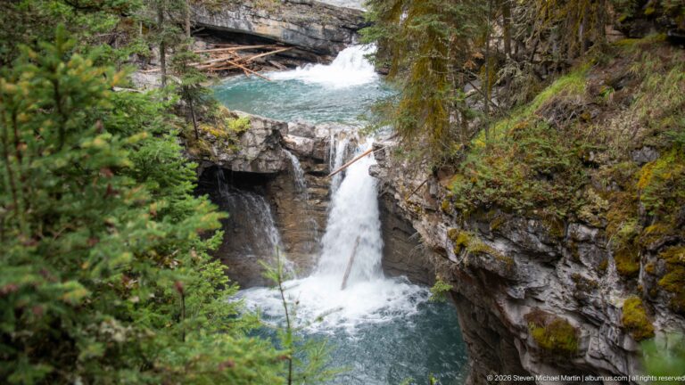 High-angle view of a creek pool and waterfall separated by a narrow rock opening.