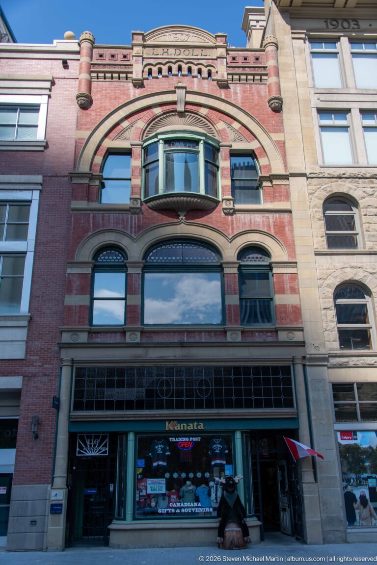 1907 Doll Block on Stephen Avenue, with red brick, sandstone arches, projecting oriel window, and DOLL carved near the roofline.