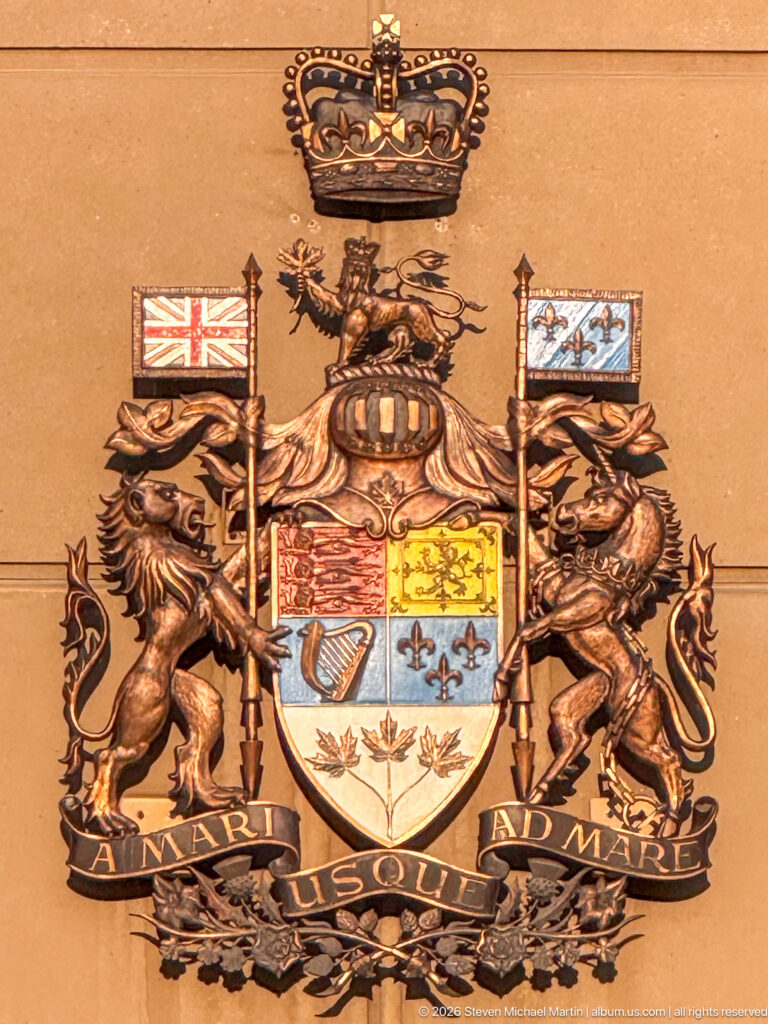 Colorful Calgary coat of arms with crown, lion, horse, flags, shield, and ONWARD motto mounted on sandstone.