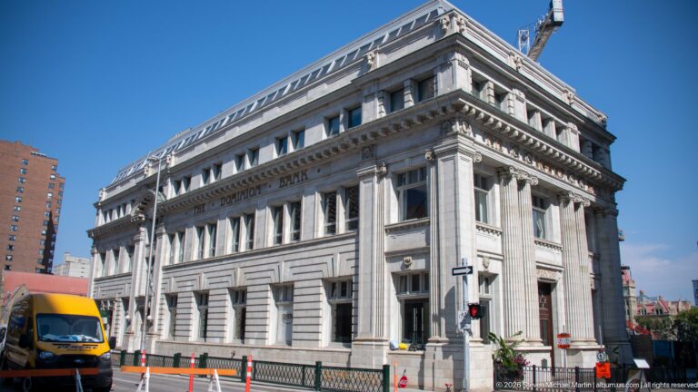 1911 Dominion Bank building on Stephen Avenue, with white terra-cotta façade, paired Ionic columns, rusticated base, and carved bank name.