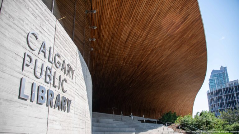 Calgary Public Library lettering on a pale wall beneath the curved wooden soffit of Calgary Central Library.