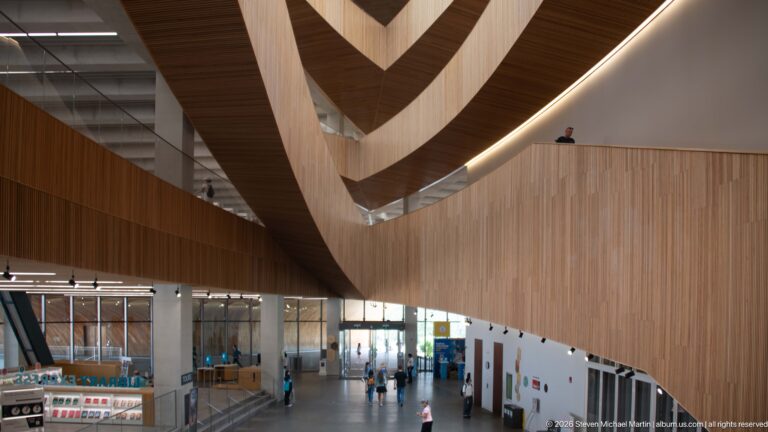 Large curved wood balcony spanning above visitors and service areas inside Calgary Central Library.