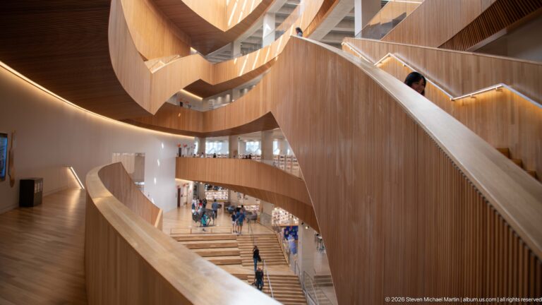Curving wood-clad balconies, ramps, and stairs overlooking the multi-level atrium of Calgary Central Library.