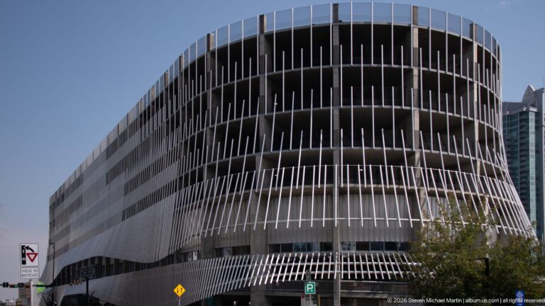Curved Calgary Central Library façade covered with closely spaced vertical fins above a downtown street.