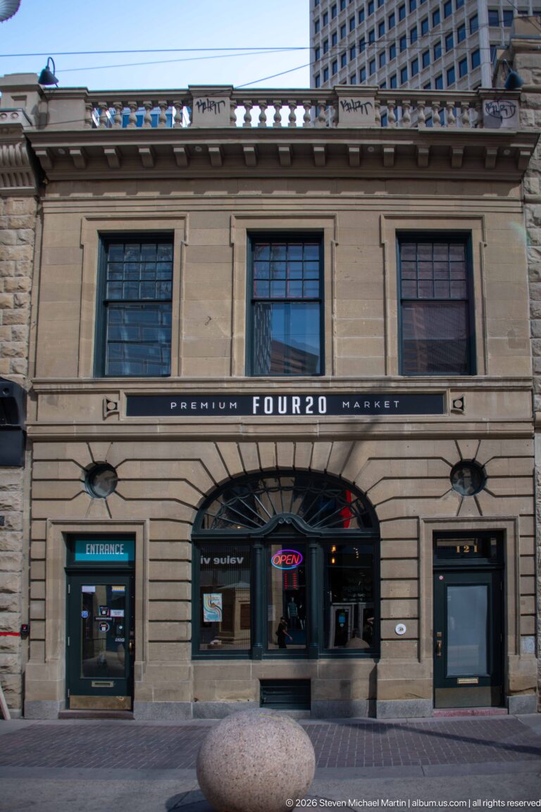 Two-story historic stone commercial building with FOUR20 storefront signage and decorative cornice on Stephen Avenue.