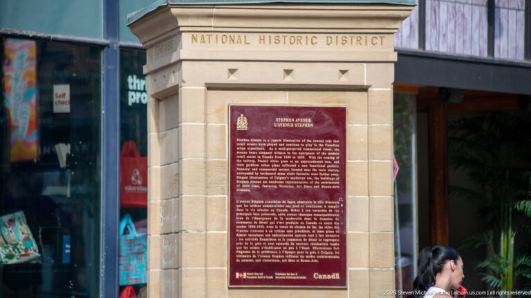 Stephen Avenue heritage plaque beneath carved words National Historic District on a downtown Calgary building.