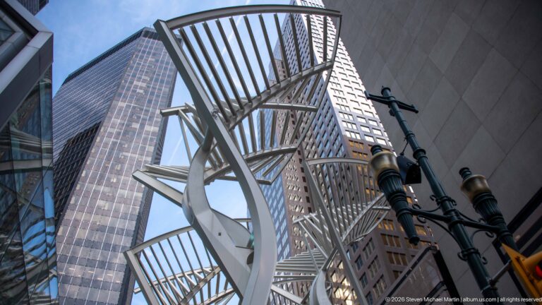 Low-angle view of Calgary’s white Galleria Trees branching into open metal canopies between downtown towers.