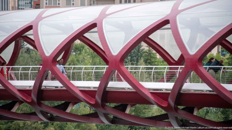Side detail of Calgary’s Peace Bridge showing interlaced red steel ribs and translucent canopy panels.