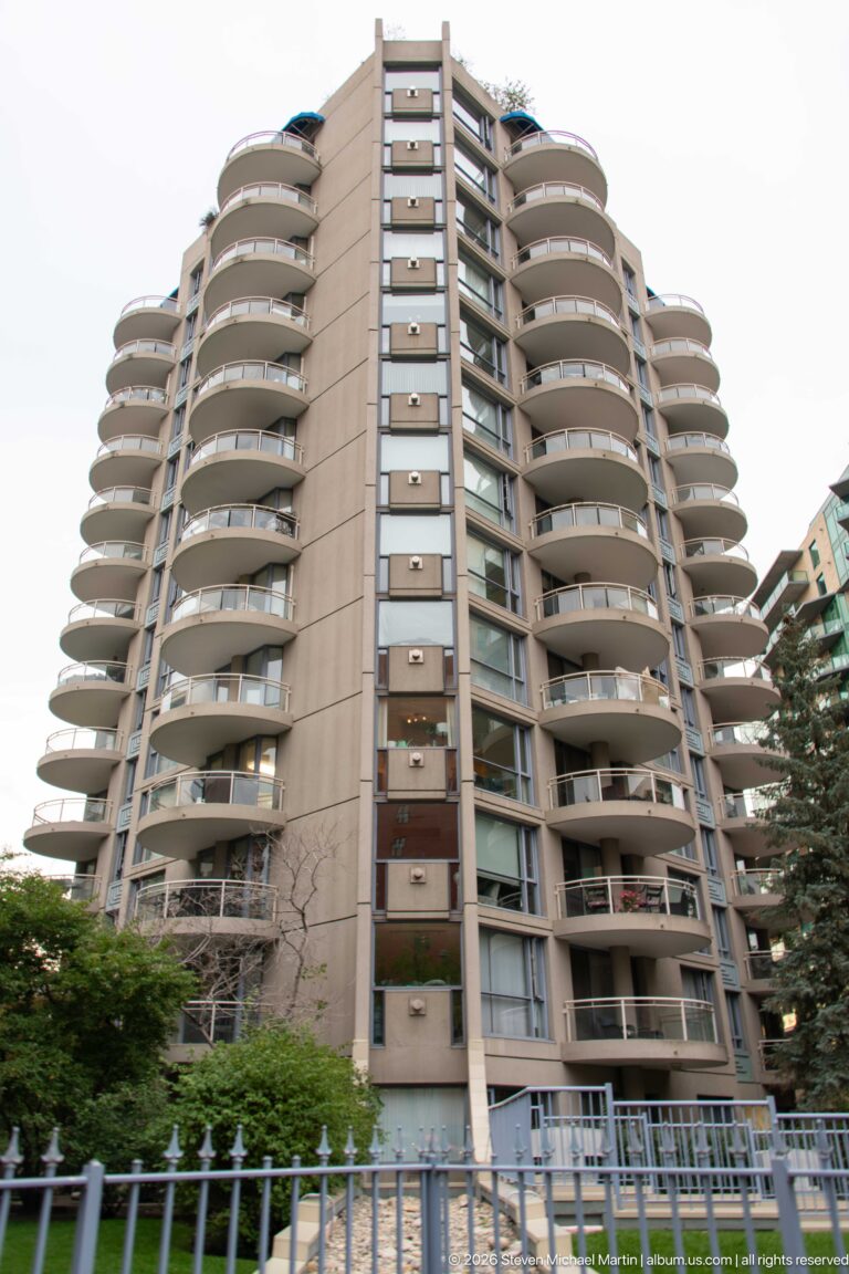 Concrete residential tower with stacked rounded balconies viewed from street level in Calgary.